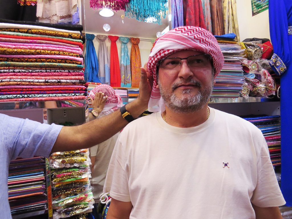 João Miguel experimenta um Keffiyeh numa loja em Dubai, Emirados Árabes