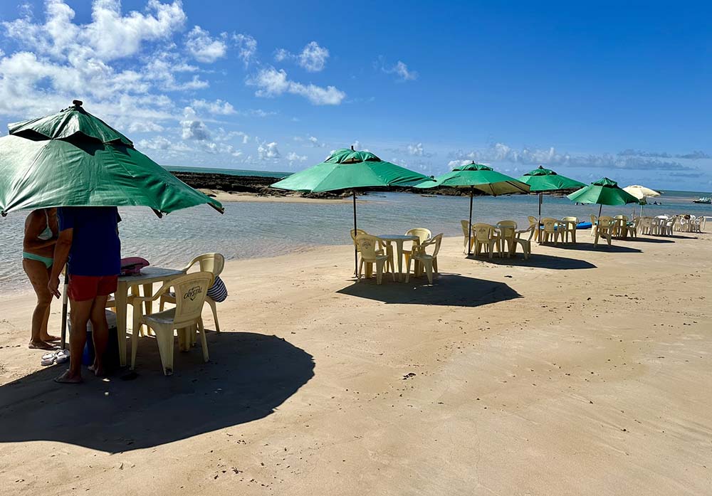 Praia do Pontal de Coruripe, com cadeiras, mesa e guarda-sol, em Alagoas