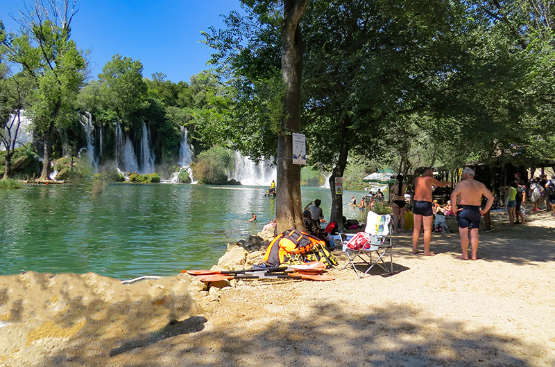 Pessoas aproveitando o dia em Kravice Falls, na Bósnia Pessoas às margens de Kravice Falls, na Bósnia