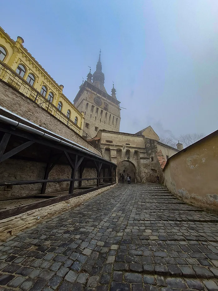 A torre do relógio envolta na neblina em Sighisoara, Romênia. Subida para Sighisoara, Romênia